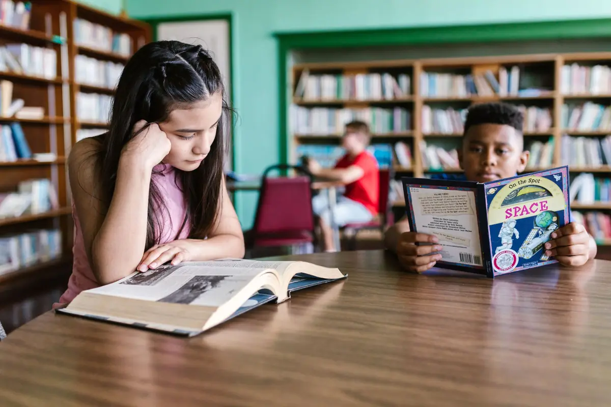 Two middle school students reading at a table in the school library
