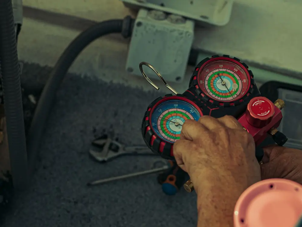 Technician reading refrigerant gauges on an air conditioner